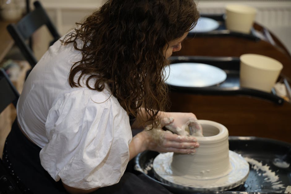 A woman skillfully crafting pottery on a wheel in a cozy studio.