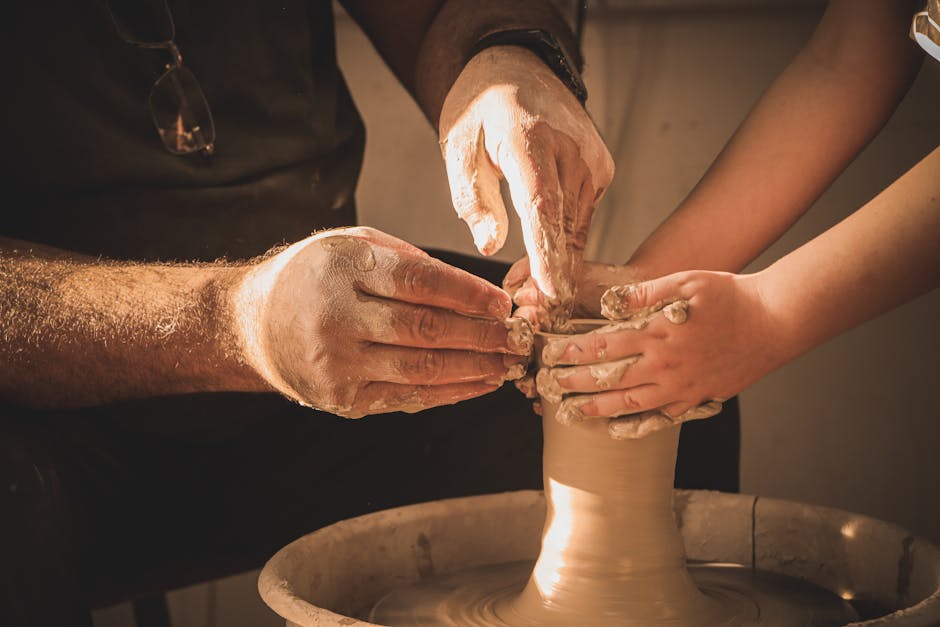 Adult and child hands working together shaping clay on a pottery wheel. Artistic collaboration in a warm, cozy setting.